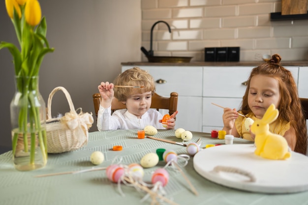 Ragazzo e ragazza divertenti decorano le uova con vernice prima delle vacanze di Pasqua