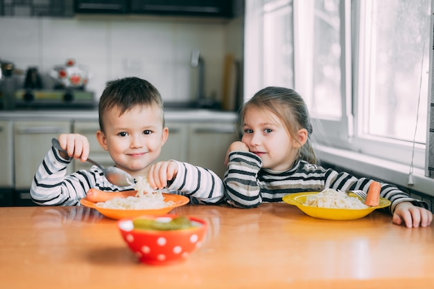 Ragazzo e ragazza in cucina a mangiare pasta