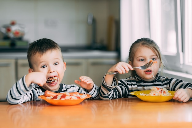 Ragazzo e ragazza in cucina a mangiare pasta