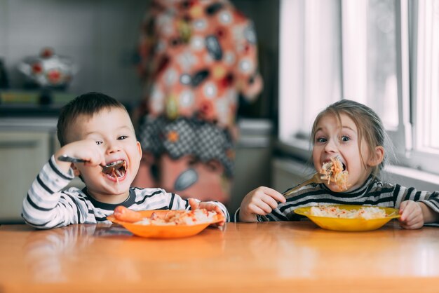 Ragazzo e ragazza in cucina a mangiare pasta