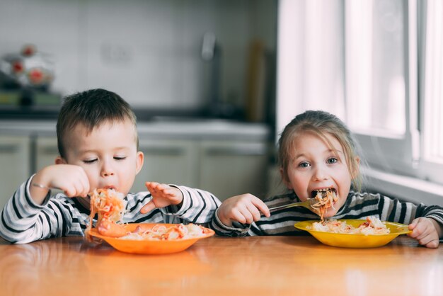 Ragazzo e ragazza in cucina a mangiare pasta