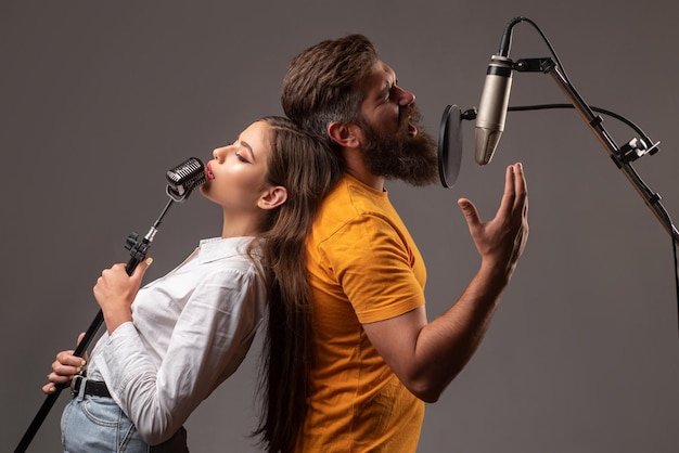 Ragazzo e signora con facce eccitate si divertono con la musica Coppia di cantanti karaoke Uomo e donna che cantano con il microfono musicale