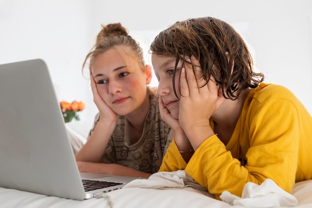 Ragazzo e sorella adolescente che condividono un computer portatile che guarda in una camera da letto