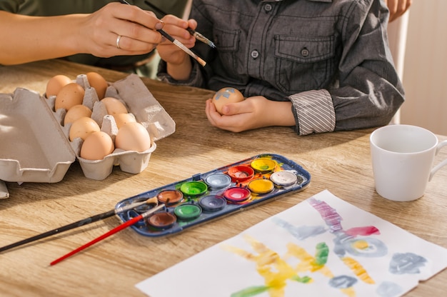 Ragazzo e sua madre dipingono le uova a Pasqua