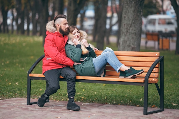 Ragazzo e una ragazza stanno riposando su una panchina in un parco in autunno
