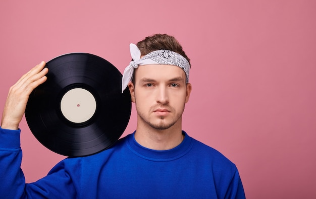 Ragazzo elegante in giacca blu scuro bandanin con disco in vinile nero in mano