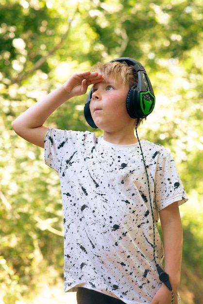 Ragazzo emotivo di 9 anni nella foresta con le cuffie per ascoltare musica