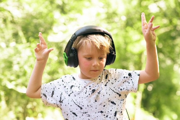 Ragazzo emotivo di 9 anni nella foresta con le cuffie per ascoltare musica