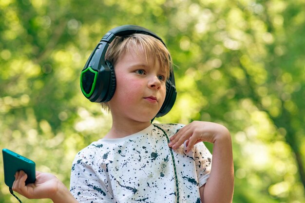 Ragazzo emotivo di 9 anni nella foresta con le cuffie per ascoltare musica