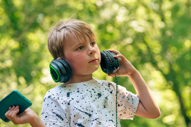 Ragazzo emotivo di 9 anni nella foresta con le cuffie per ascoltare musica