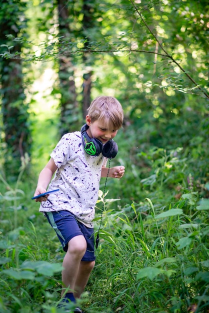 Ragazzo emotivo di 9 anni nella foresta con le cuffie per ascoltare musica