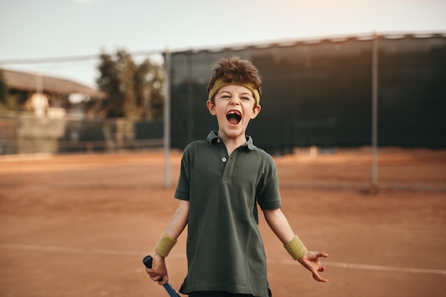 Ragazzo emozionante che celebra la vittoria sul campo da tennis