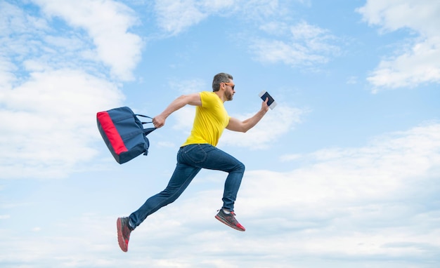 Ragazzo energico in esecuzione con la vacanza di sfondo del cielo a mezz'aria borsa da viaggio