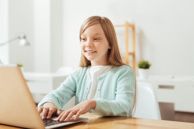 Ragazzo esperto. Ragazza produttiva piuttosto ammirevole usando il suo computer mentre era seduto al tavolo