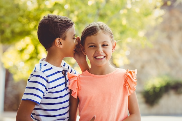 Ragazzo felice che bisbiglia un segreto nell'orecchio delle ragazze