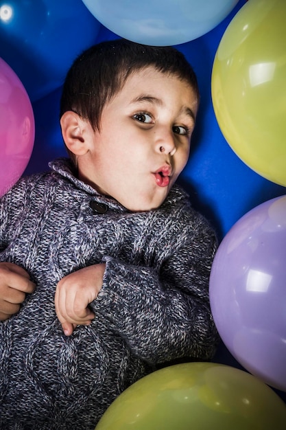 Ragazzo felice che gioca con palloncini di molti colori