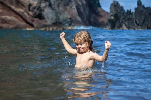 Ragazzo felice che gioca e in piscina o in acqua di mare divertente per bambini viso estivo