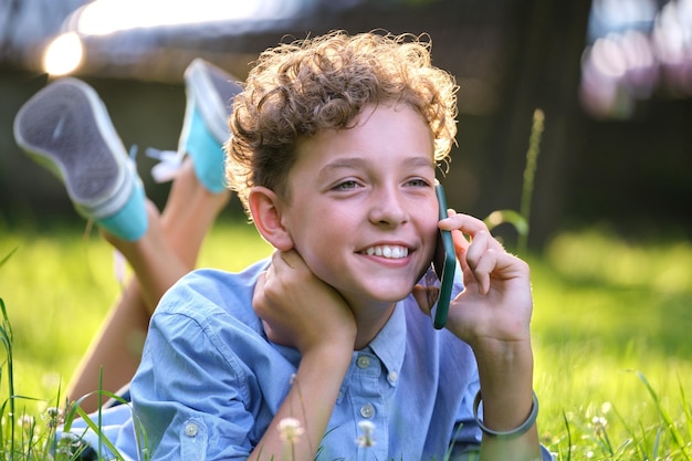 Ragazzo felice che parla al cellulare all'aperto nel parco estivo