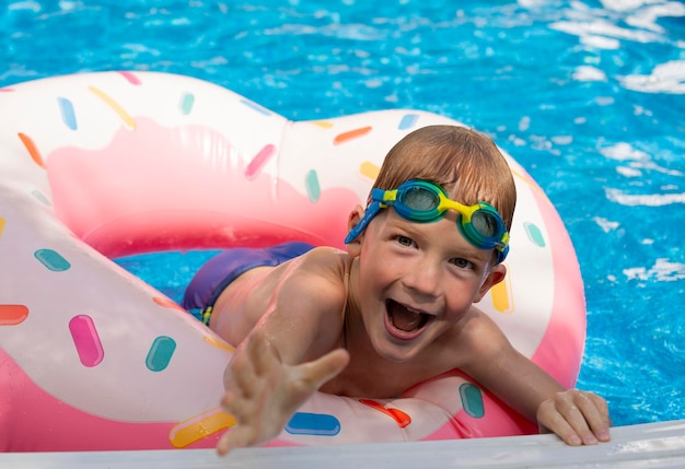 ragazzo felice con i googles in piscina su ciambelle da bagno estate e attività in acqua