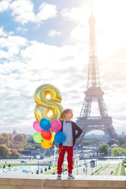 Ragazzo felice con un mazzo di palloncini colorati a Parigi vicino alla Torre Eiffel.