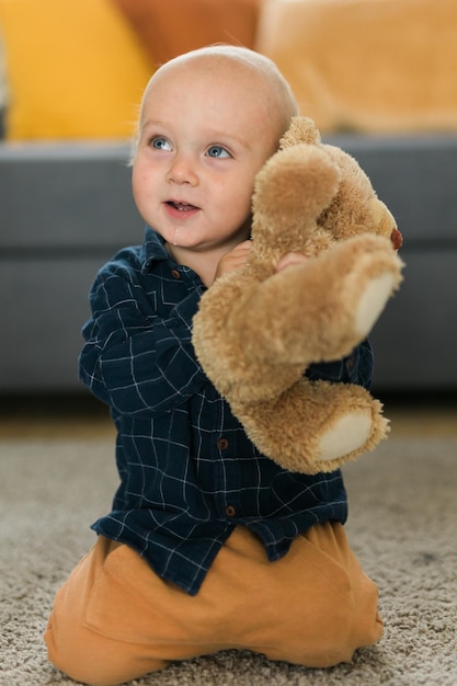 Ragazzo felice del bambino che gioca con il suo orsacchiotto a casa infanzia e fasi di sviluppo del bambino concep