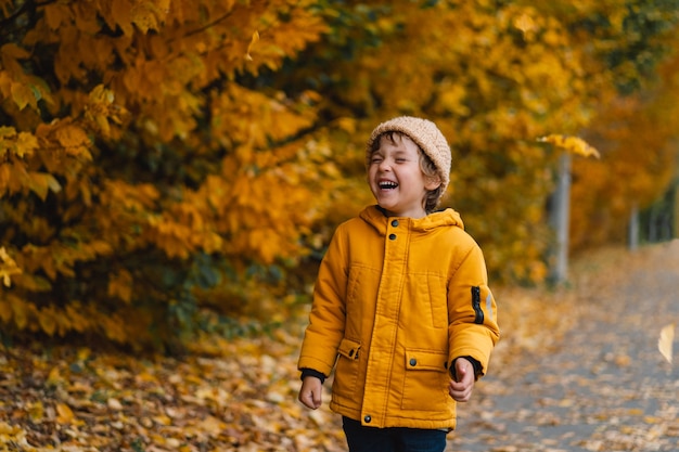 Ragazzo felice del bambino che ride e che gioca nel giorno di autunno.