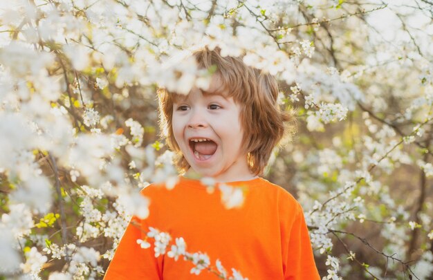 Ragazzo felice di primavera con albero in fiore estate parco giardino concetto ragazzo sorridente all'aperto