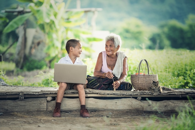 Ragazzo felice e nonna che per mezzo del computer portatile