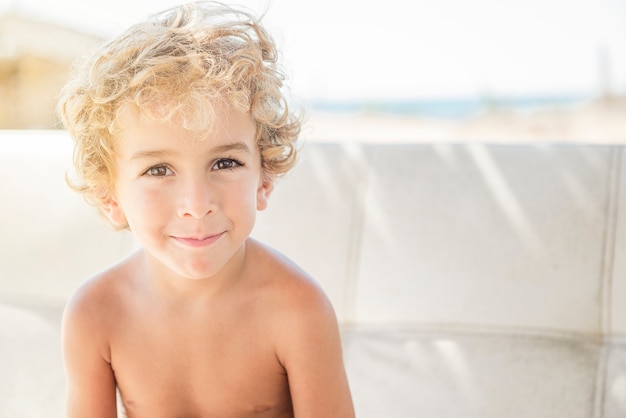 Ragazzo felice sulla spiaggia che sorride alla macchina fotografica