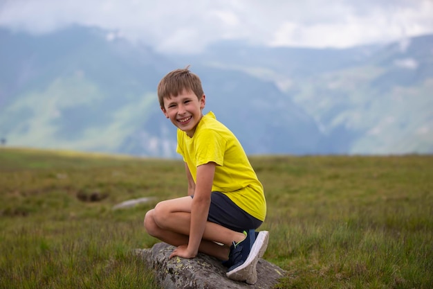 Ragazzo felice sullo sfondo di un paesaggio di montagna guardando la telecamera e sorridente