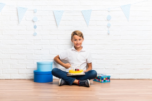 Ragazzo festeggia il suo compleanno con una torta in posa con le braccia all&#39;anca