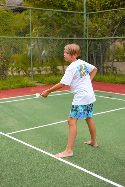 ragazzo gioca a badminton all'aperto all'aria fresca lancia una navetta e tiene una racchetta un'isola nelle Maldive ricreazione attiva e sport.