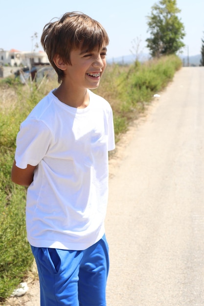 Ragazzo giovane biondo in camicia bianca e pantaloncini blu che si gode il sole estivo in natura