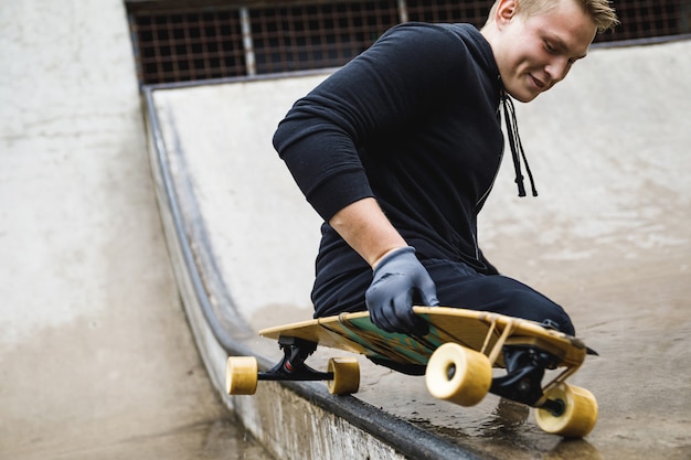 Ragazzo giovane e motivato con handicap con un longboard nello skatepark