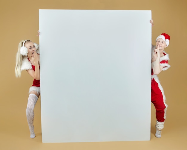 Ragazzo giovane e una ragazza in costumi di Babbo Natale su un layout pubblicitario. Concetto di Natale e Capodanno