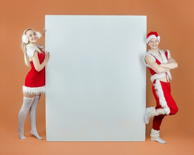 Ragazzo giovane e una ragazza in costumi di Babbo Natale su un layout pubblicitario. Concetto di Natale e Capodanno