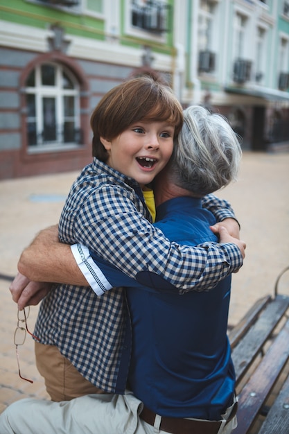 Ragazzo giovane felice che sembra eccitato che abbraccia suo nonno