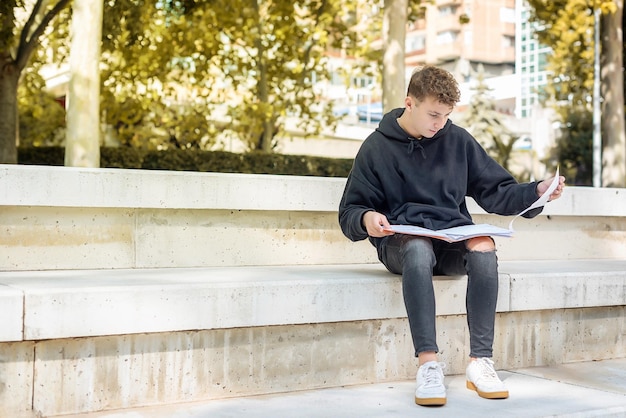 Ragazzo giovane studente guardando i suoi appunti all'università