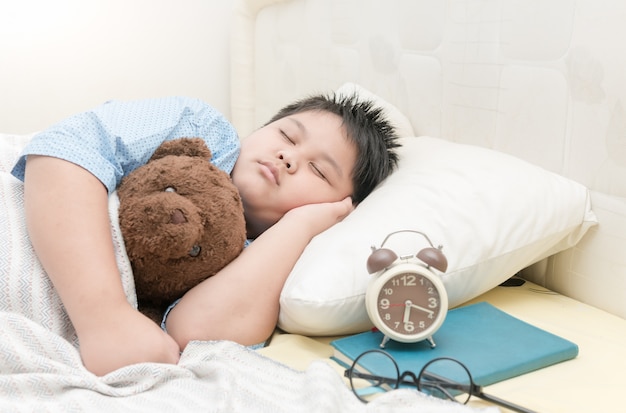 ragazzo grasso dormire e abbracciare orsacchiotto sul letto