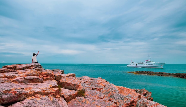 Ragazzo in attesa presso la formazione rocciosa colorata nel mare intorno alla pittoresca cittadina Gudhjem a Bornholm, Danimarca