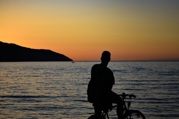 Ragazzo in bicicletta che guarda il tramonto