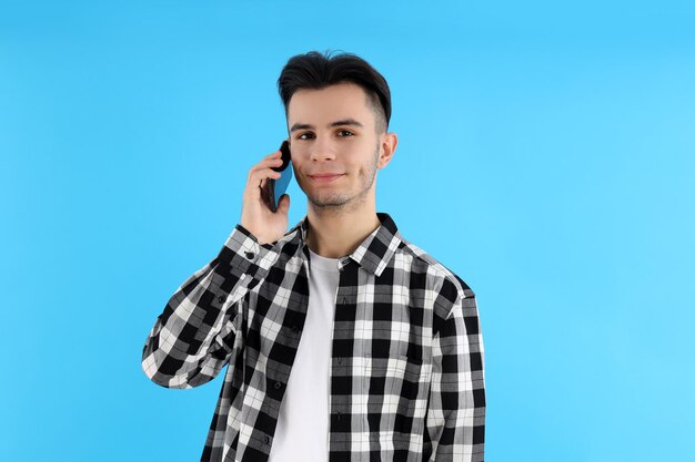 Ragazzo in camicia con telefono su sfondo blu