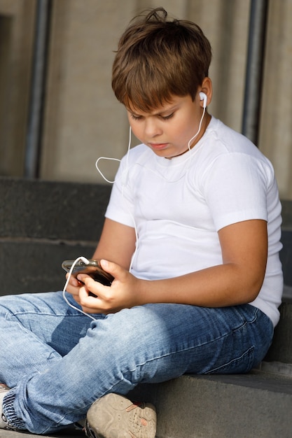 Ragazzo in cuffie con smartphone ascolta musica nel parco