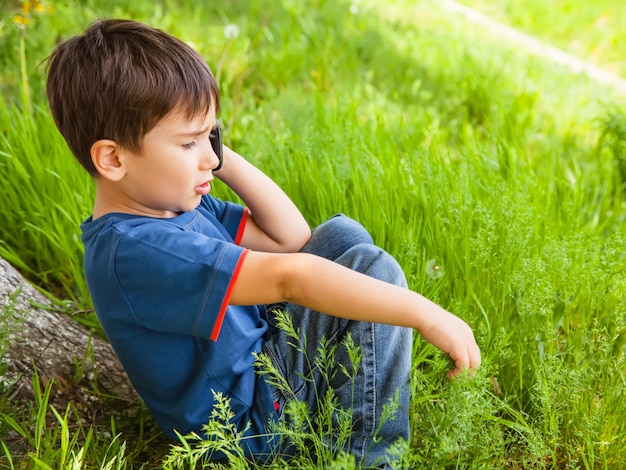 Ragazzo in erba verde che parla sul telefono cellulare