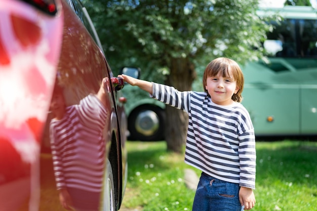 Ragazzo in età prescolare che apre una porta dell'auto di famiglia sul parcheggio bambino pronto a sedersi in una cassaforte per auto che viaggia con i bambini