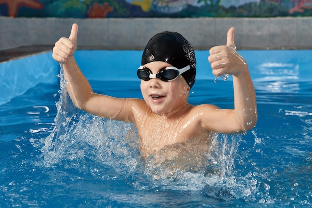 Ragazzo in età prescolare che impara a nuotare in una piscina con cuffia e occhiali