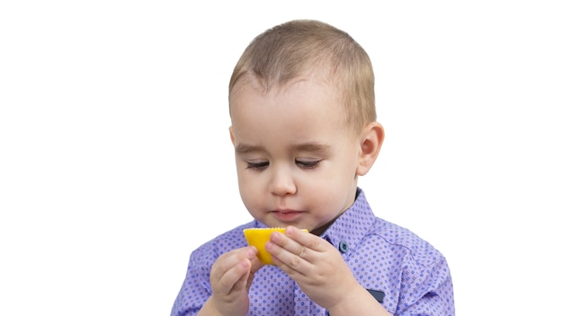 Ragazzo in età prescolare che mangia limone acido, sfondo bianco isolato.