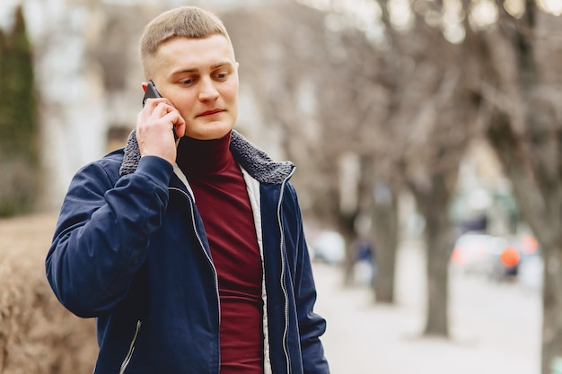 Ragazzo in giacca semplice sta con telefono