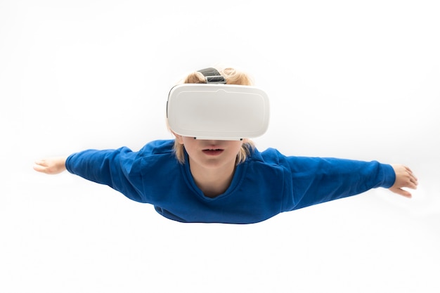 Ragazzo in occhiali per realtà virtuale vola su superficie bianca. Giochi di realtà virtuale, occhiali VR.