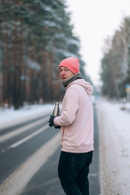 Ragazzo in piedi sulla strada in mezzo alla foresta circondata dalla neve